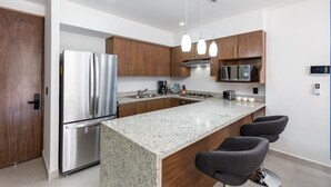A modern kitchen with stainless steel appliances, wooden cabinets, granite countertops, and pendant lighting.