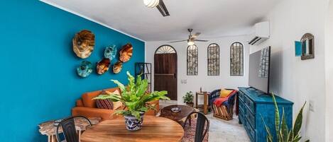 Un coin repas avec une table ronde en bois, des chaises et un ventilateur de plafond.