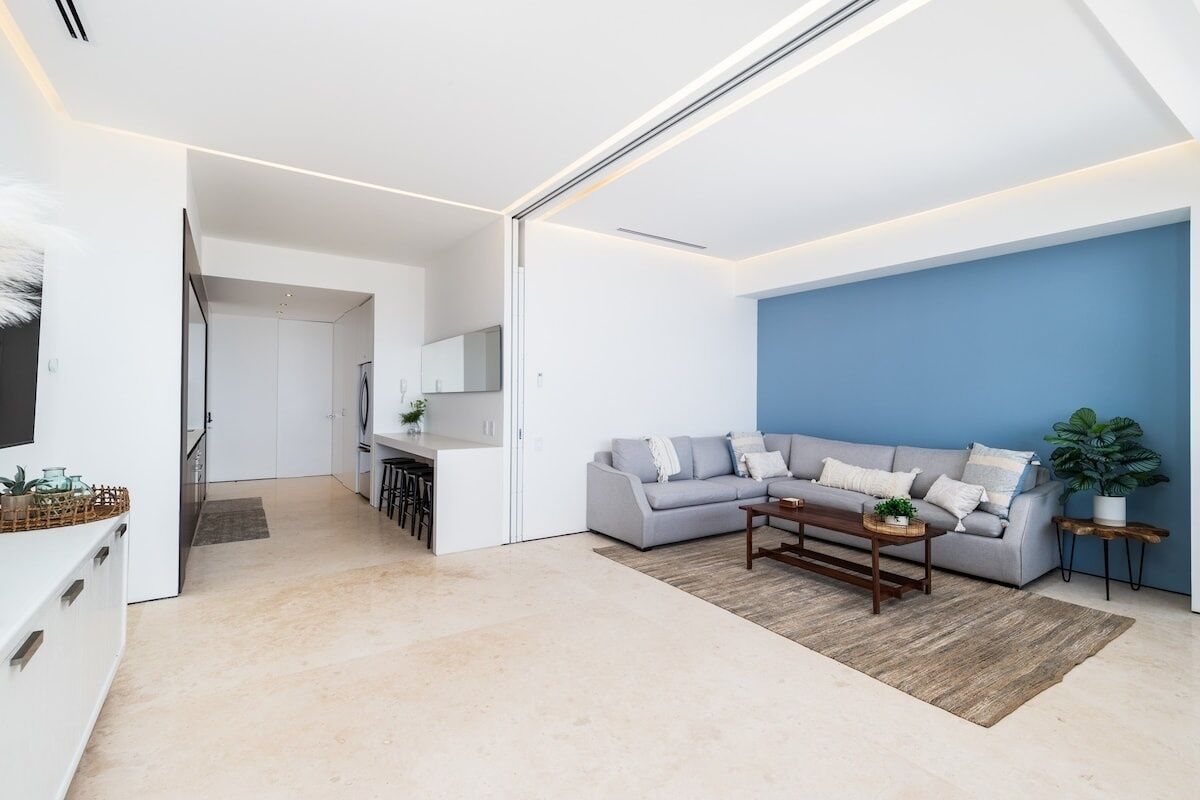 Una sala de estar moderna con un sofá gris, una mesa de centro y una pared de acento azul.
