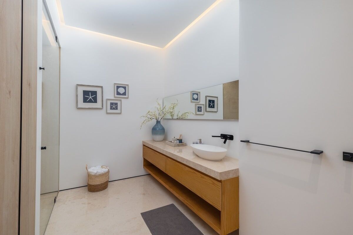 A modern bathroom with a white vanity, a large mirror, and framed artwork on the wall.