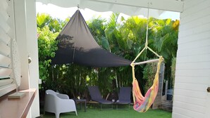 Un espace patio avec une table blanche, des chaises et un hamac suspendu.