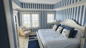Un dormitorio con una cama grande, paredes a rayas y vistas al exterior.
