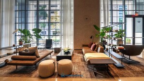 A spacious hotel lobby with large windows, a modern sofa set, a coffee table, and a bookshelf. - Apartment in New Luxury Condo Downtown (Miami)