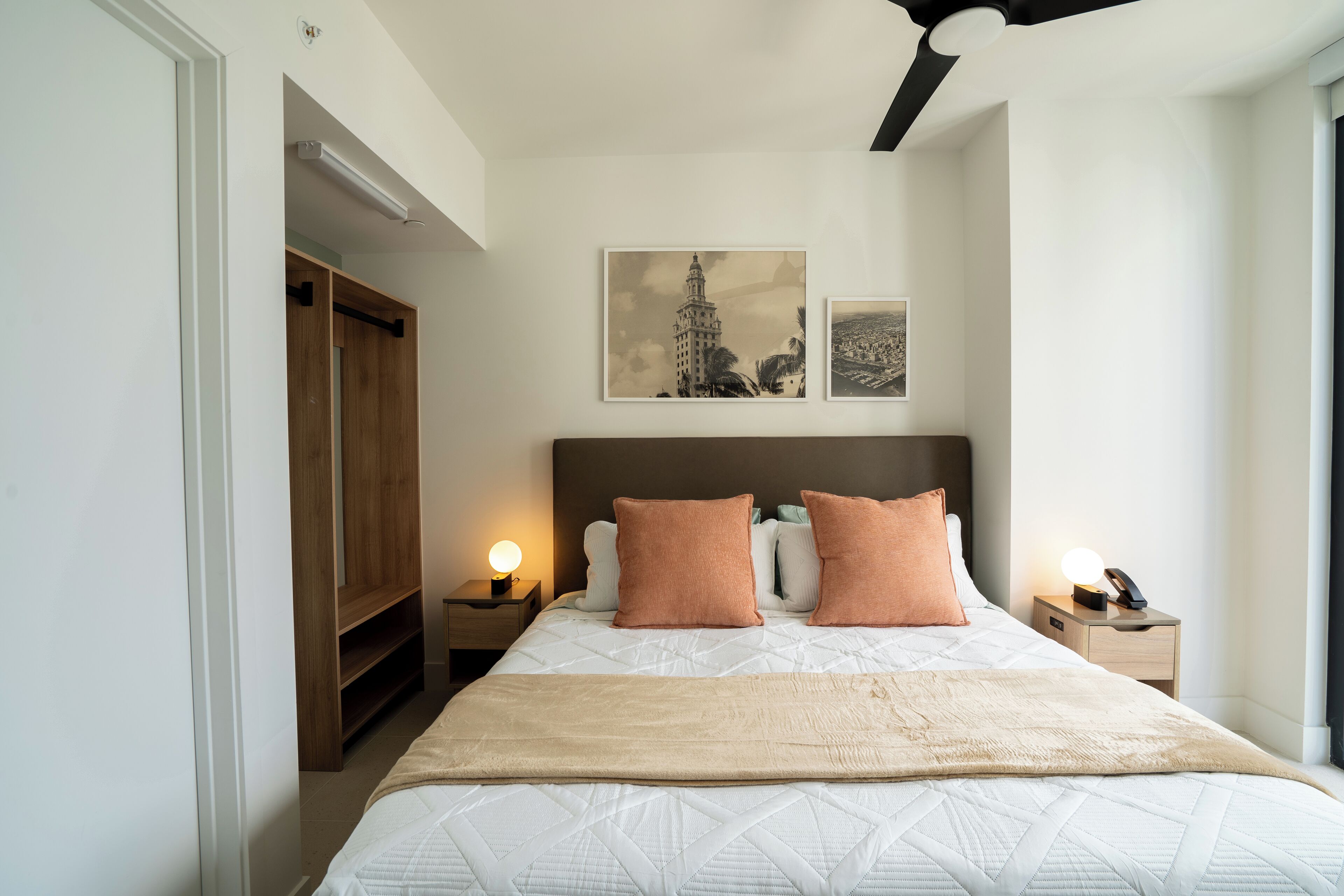 Ein Schlafzimmer mit einem Bett, zwei Nachttischen, einem Holzschrank und zwei Wandbildern.