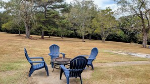 Un  ’area picnic con sedie blu e un tavolo rotondo, sullo sfondo alberi e prato.