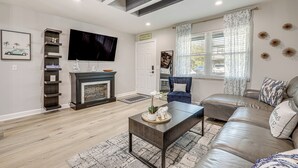 A modern living room with a fireplace, leather sofa, and a flat-screen TV. - Ponte Vedra Beach Getaway w/ Patio! (Ponte Vedra Beach)