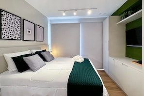 A modern bedroom with a bed, pillows, a green throw, and framed artwork on the wall. - Vossa Bossa Moema (São Paulo)