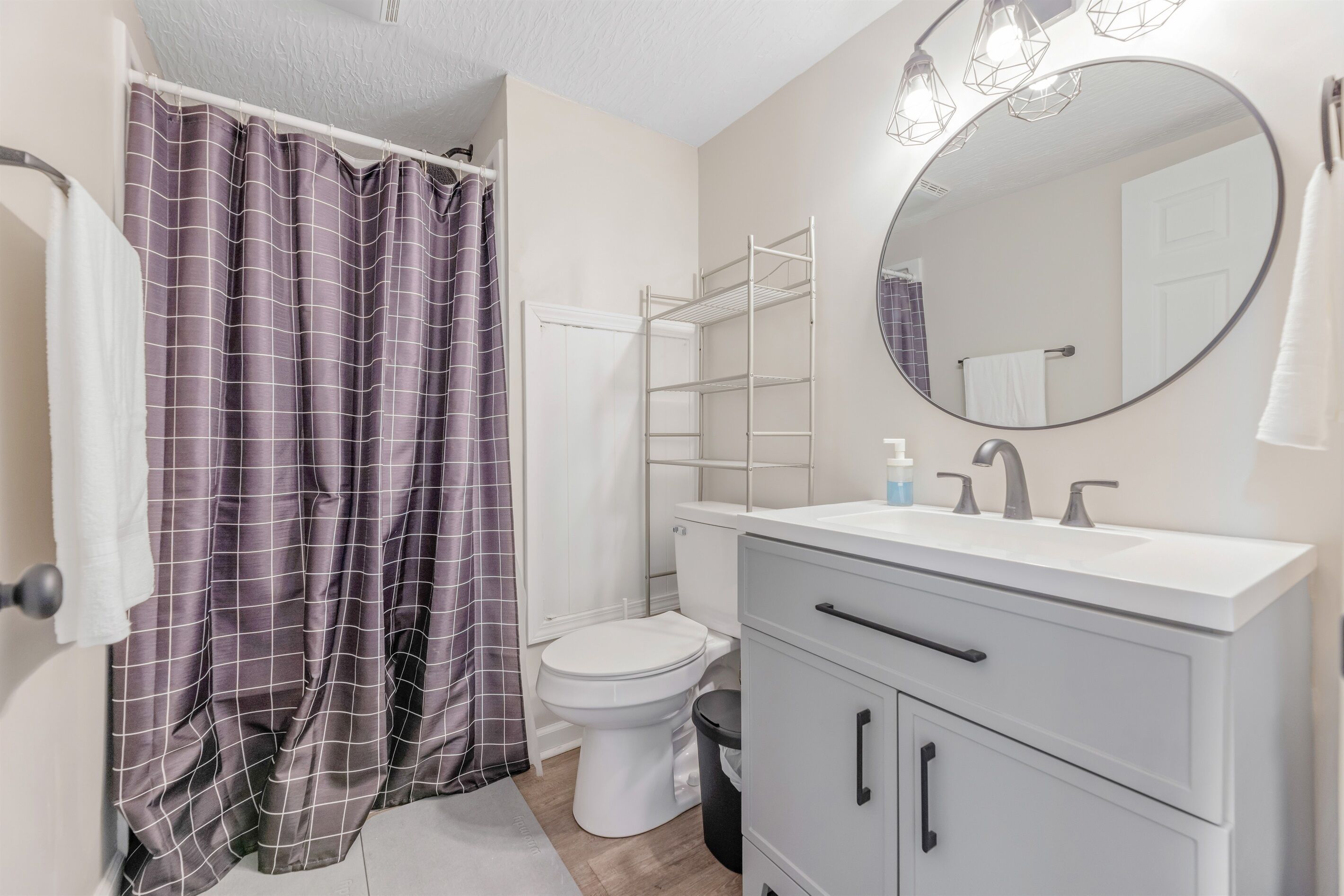 A bathroom with a white toilet, a white sink with a mirror above it, and a shower curtain.