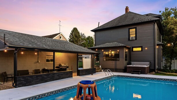 A swimming pool with an inflatable play structure, a covered patio area, and a house with a dark exterior. - Live the Game: Pool, Cinema, Gym, Jersey Wall (Massillon)
