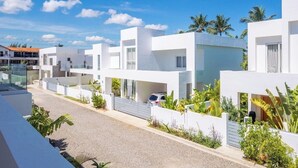 Uma área residencial moderna com edifícios brancos, céu claro e áreas verdes.