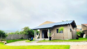 Una casa de un piso con techo de tejas, un porche delantero y un pequeño jardín.