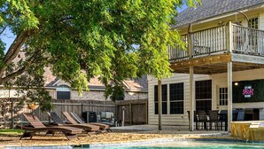 A pool area with lounge chairs, a wooden deck, and a building with a balcony.