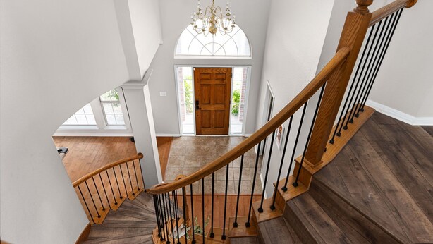 A wooden staircase with a curved design, leading to a door with a glass panel above it.