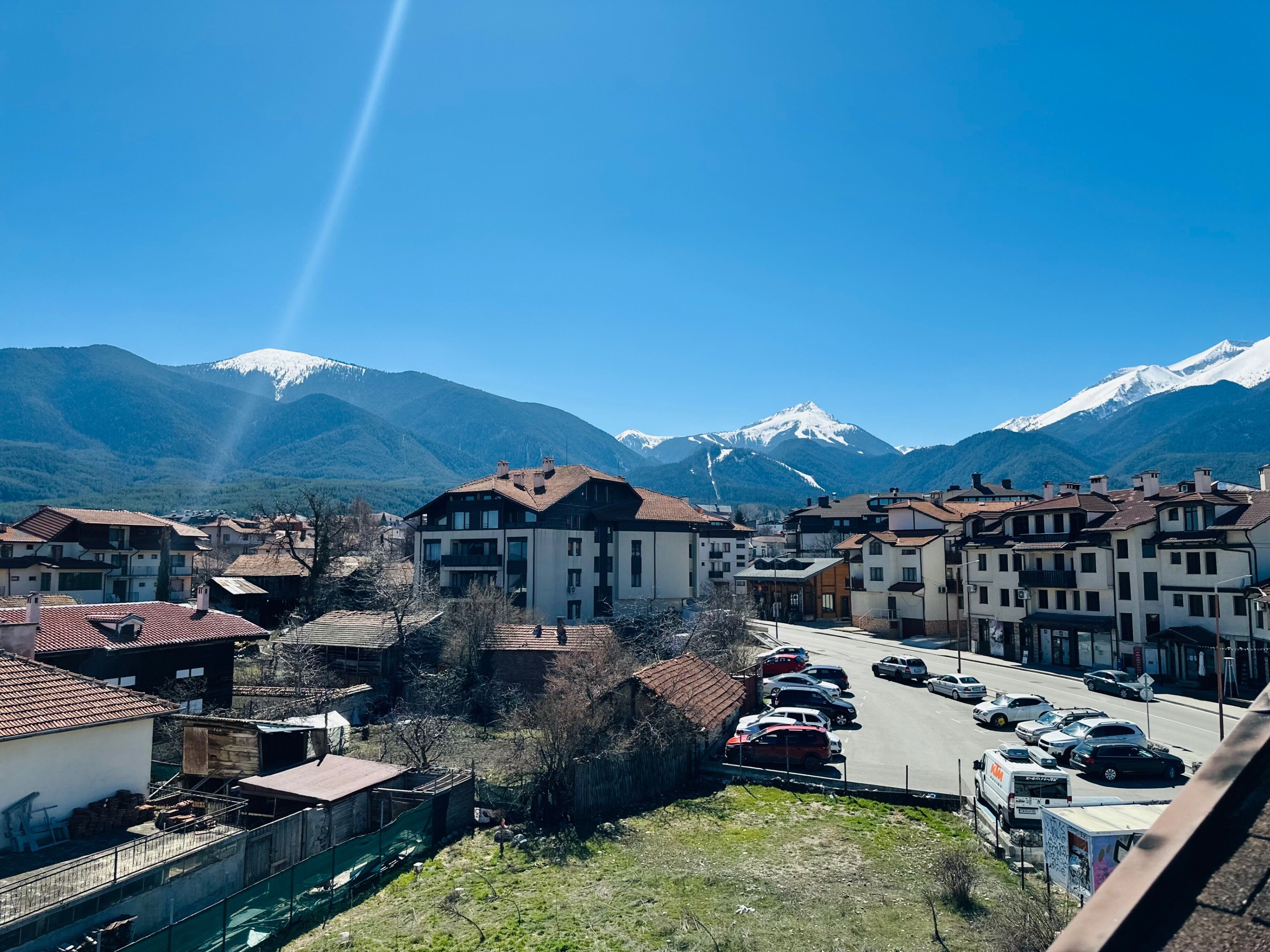 A town with buildings and a road, surrounded by mountains.