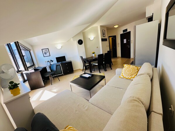 Un salon moderne comprenant un canapé, une table à manger et un espace de travail.