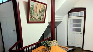 A dining area with a wooden table and chairs, a painting on the wall, and a white door with frosted glass panels. - Ideal for relaxation and excursions (Sohland an der Spree)