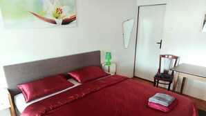 A neatly made bed with red bedding, a green lamp on a bedside table, and a chair in the corner. - Ideal for relaxation and excursions (Sohland an der Spree)
