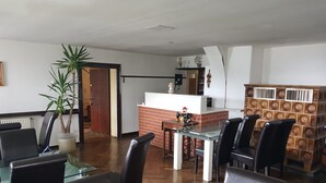A dining area with a glass table, black chairs, a brick counter, and a potted plant. - Ideal for relaxation and excursions (Sohland an der Spree)