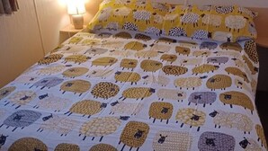 Un lit recouvert d’une courtepointe à motifs représentant différents motifs de moutons.