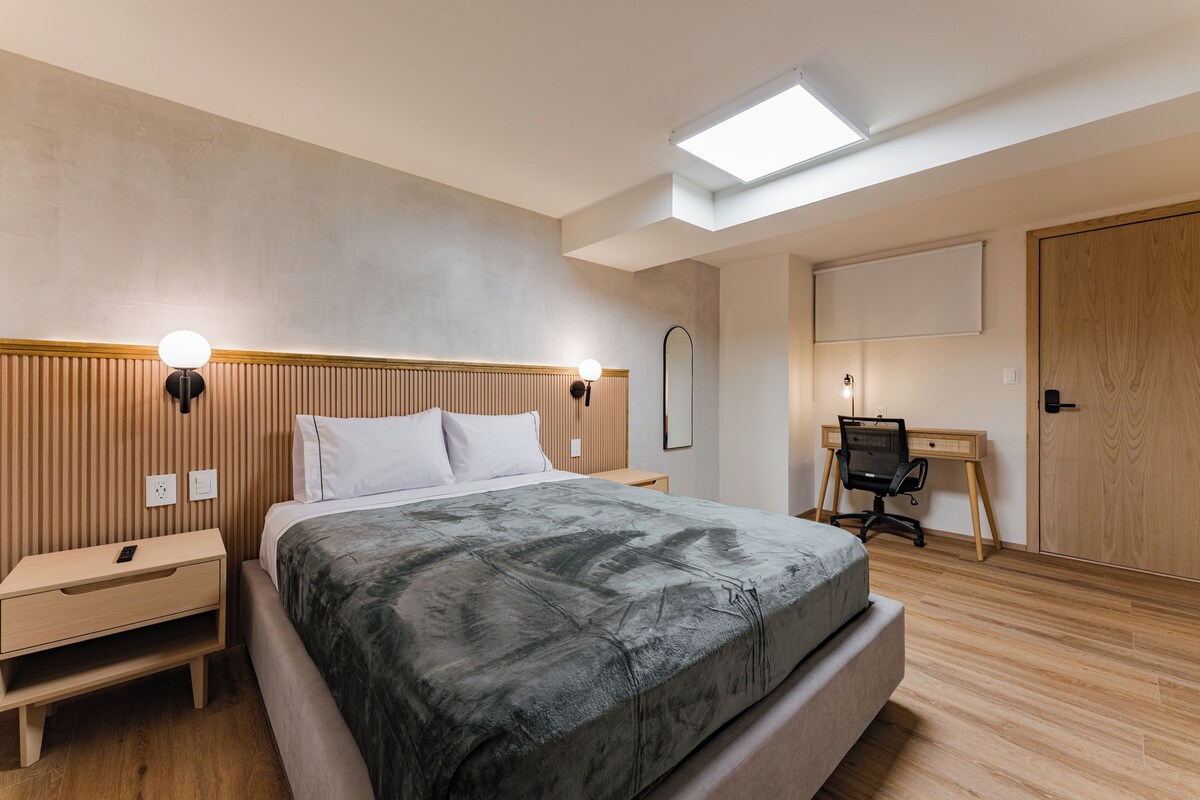Un dormitorio moderno con una cama grande, mesitas de noche, un escritorio y un armario.