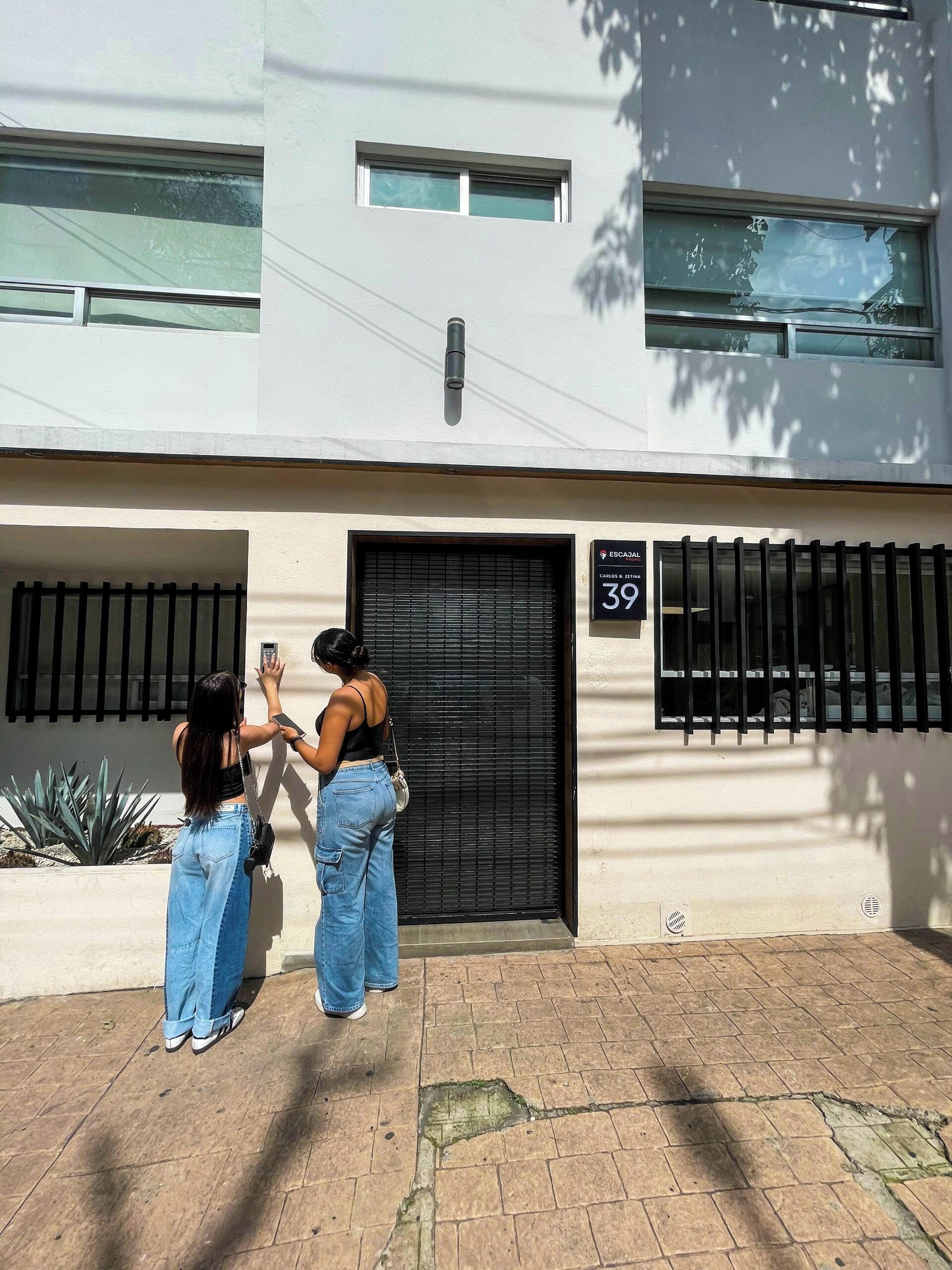 Un edificio con una reja negra, un cartel con el número 39 y una pequeña ventana sobre la reja.