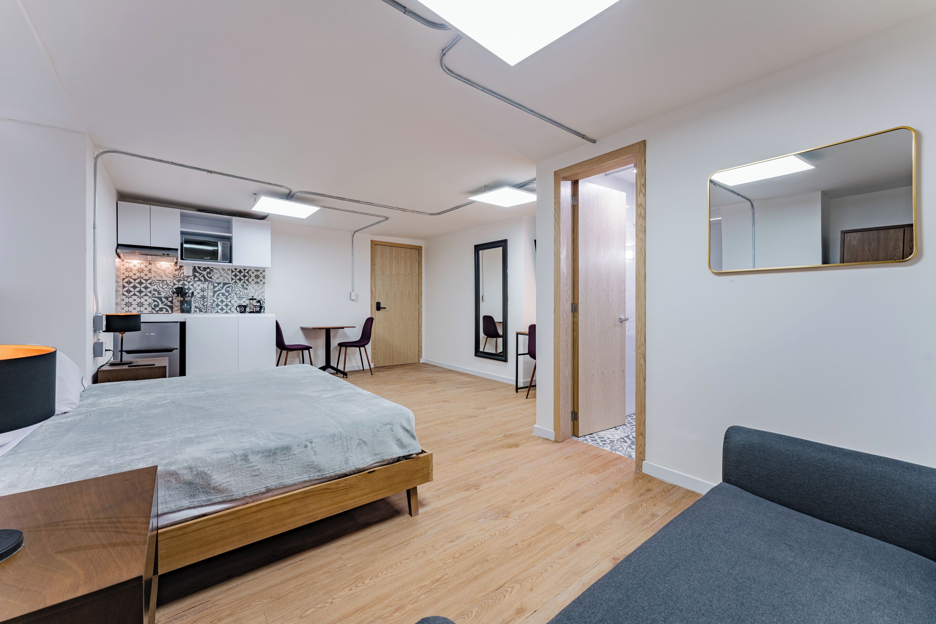 Una habitación moderna y bien iluminada con una cama, un escritorio y un comedor.