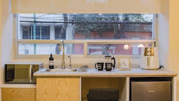Una cocina compacta con lavabo, cafetera, microondas y refrigerador.