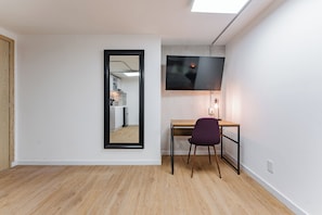 Relax in a serene space with a large mirror, flat-screen TV, and comfortable chair.
