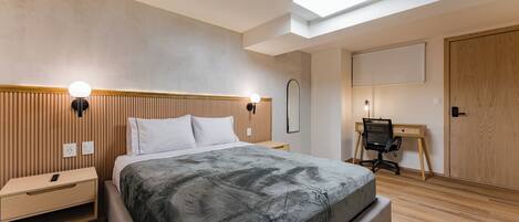 Un dormitorio moderno con una cama grande, mesitas de noche, un escritorio y un armario.