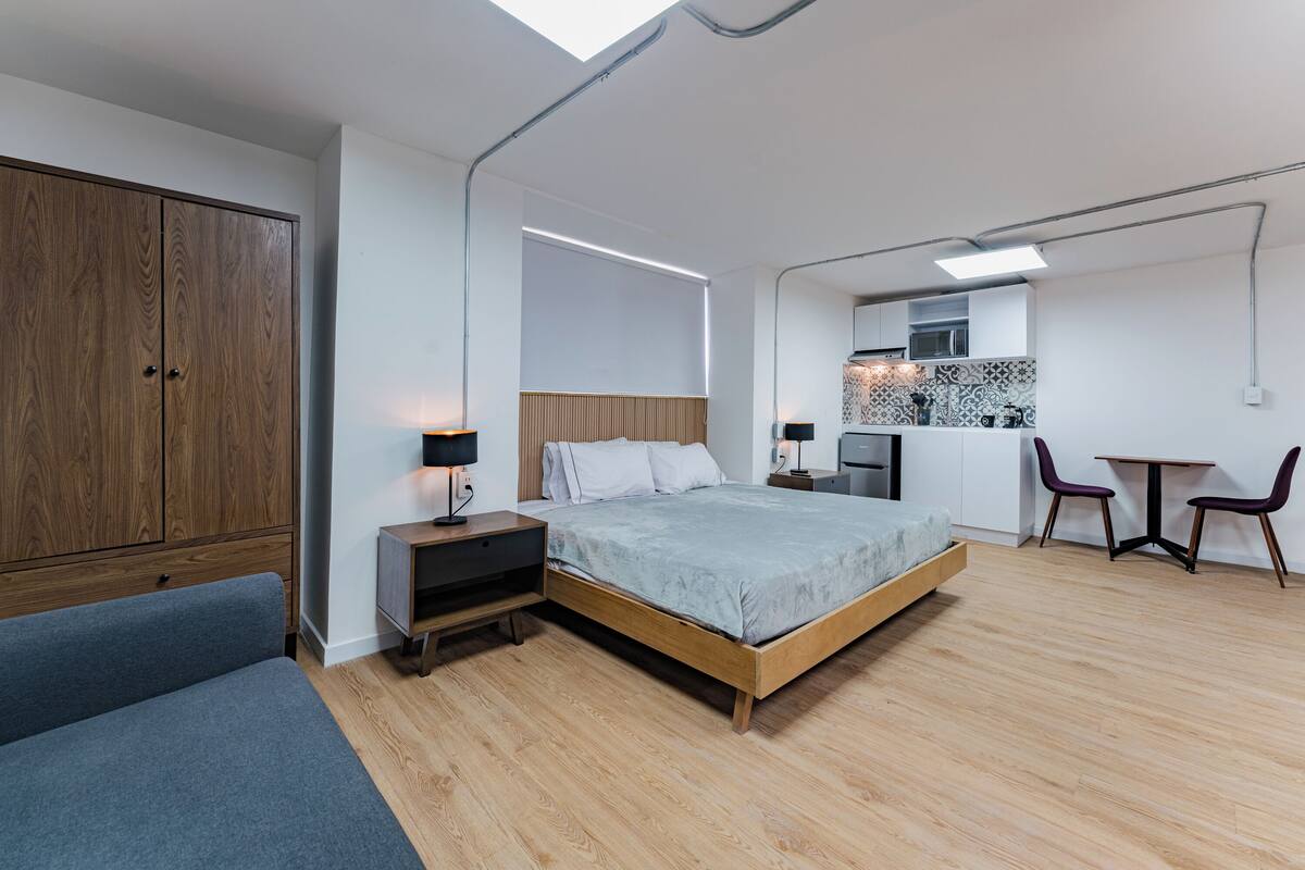Een moderne slaapkamer met een bed, nachtkastjes, een kledingkast, een bureau en een stoel.