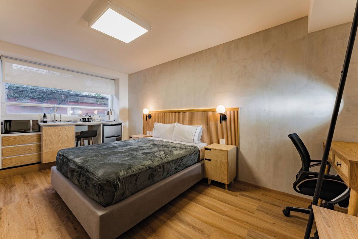 A modern bedroom with a bed, bedside tables, a desk, and a chair.