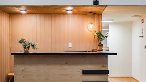 A reception desk with a wooden finish, a potted plant, and a hanging light fixture. - Escandon Suites by Escajal Room (Mexico City)