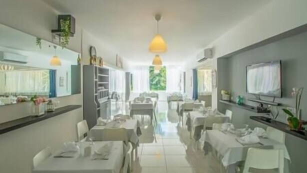 A spacious dining area with tables and chairs, pendant lighting, and a television on the wall.