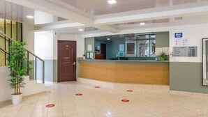 A reception area with a wooden counter, a reception desk, and a staircase on the left.