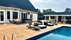 Ein Swimmingpool mit Liegestühlen und einer überdachten Terrasse.