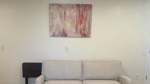 A neutral-toned sofa in a room with a textured wall and a single power outlet.