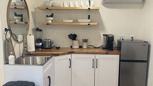 A compact kitchen with white cabinets, a stainless steel sink, and a built-in refrigerator.
