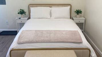 A neatly made bed with a matching bench, two bedside tables with lamps, and a wall clock.