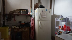 Cocina compacta con un refrigerador blanco, estufa y un estante con diferentes utensilios de cocina.