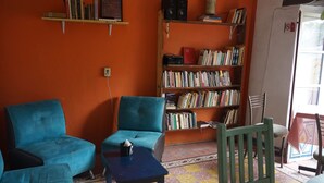 Una habitación con dos sillones azules, una mesita, una estantería y una silla.