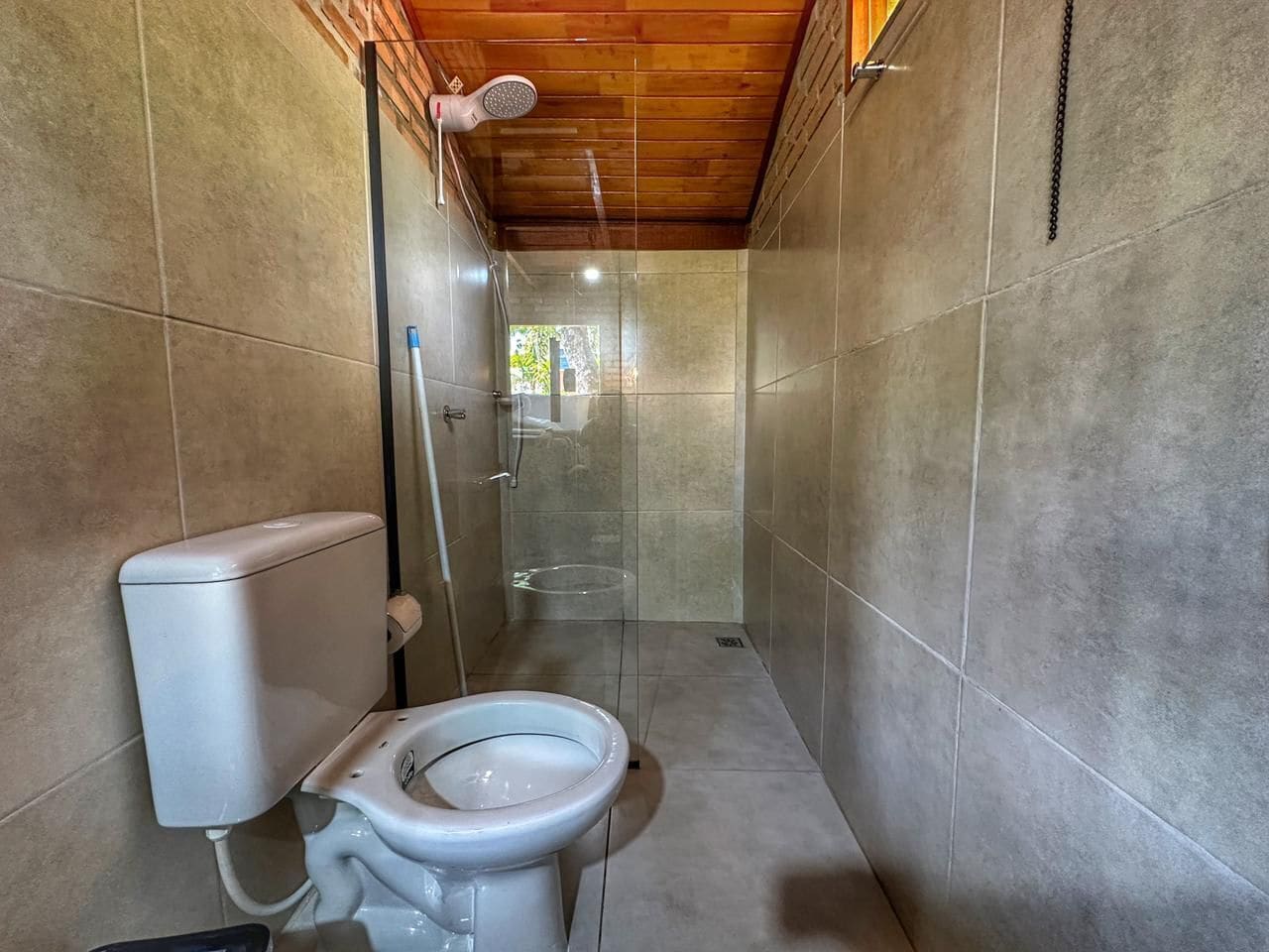 Een kleine badkamer met toilet, douche en een glazen deur naar de douchecabine.