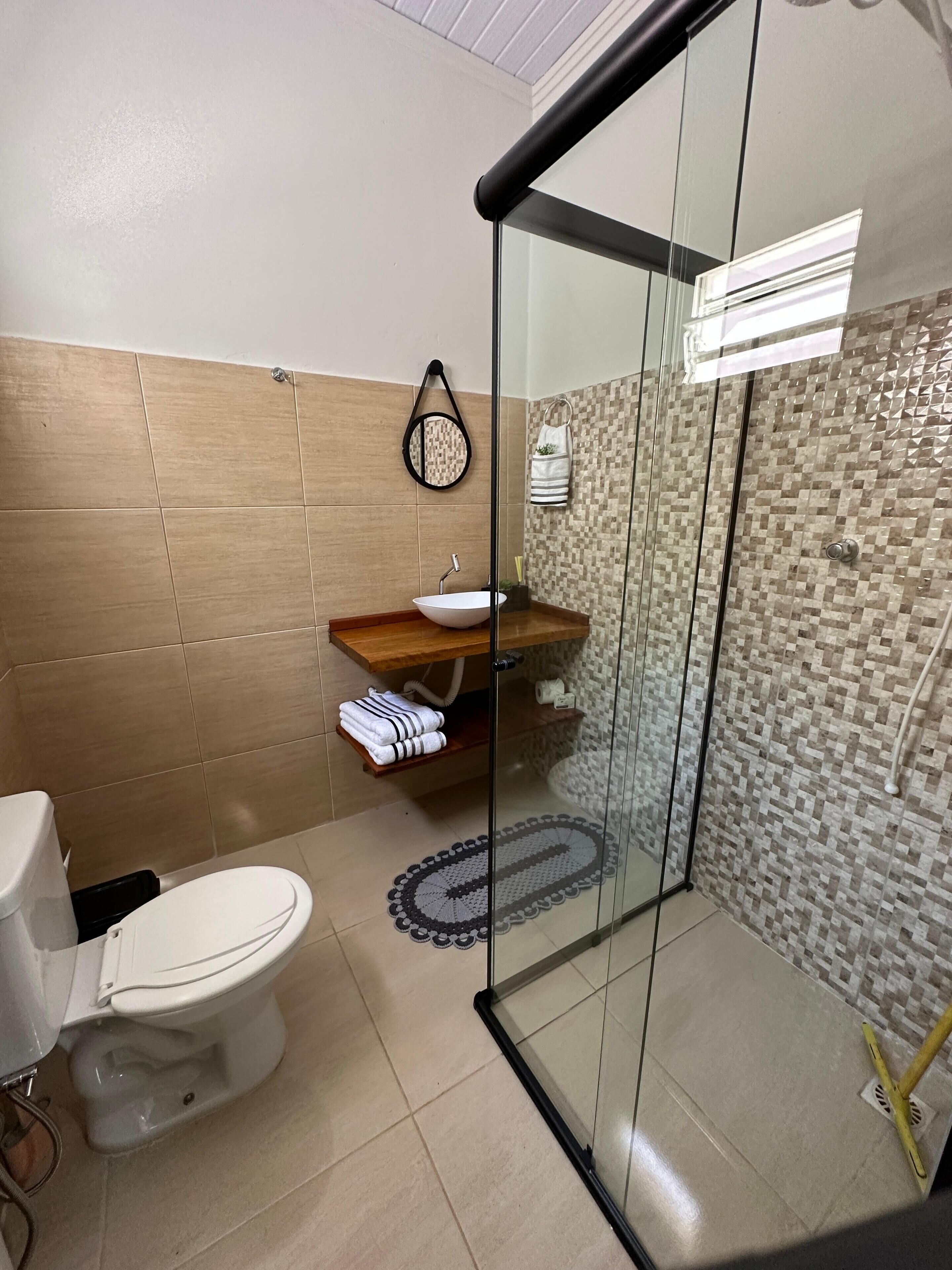 A modern bathroom with a glass-enclosed shower, a white toilet, and a wooden vanity with a sink.