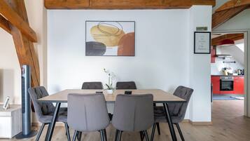 Un coin repas avec une table en bois, des chaises à revêtement gris et un tableau abstrait moderne accroché au mur.