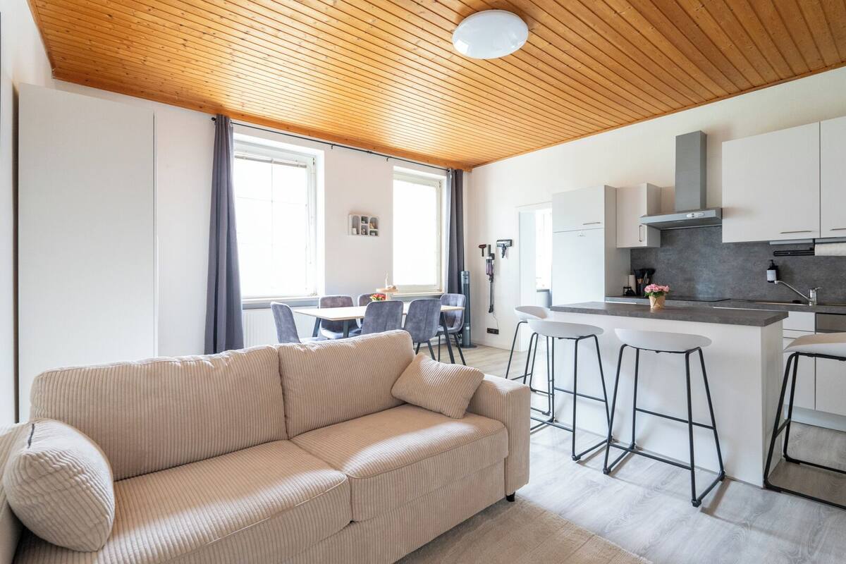 A modern living room with a sofa, dining area, and kitchen.