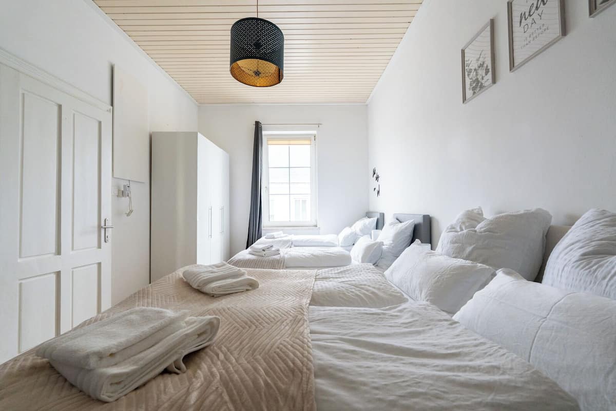 A hotel room with two beds, a large window, and a hanging light fixture.