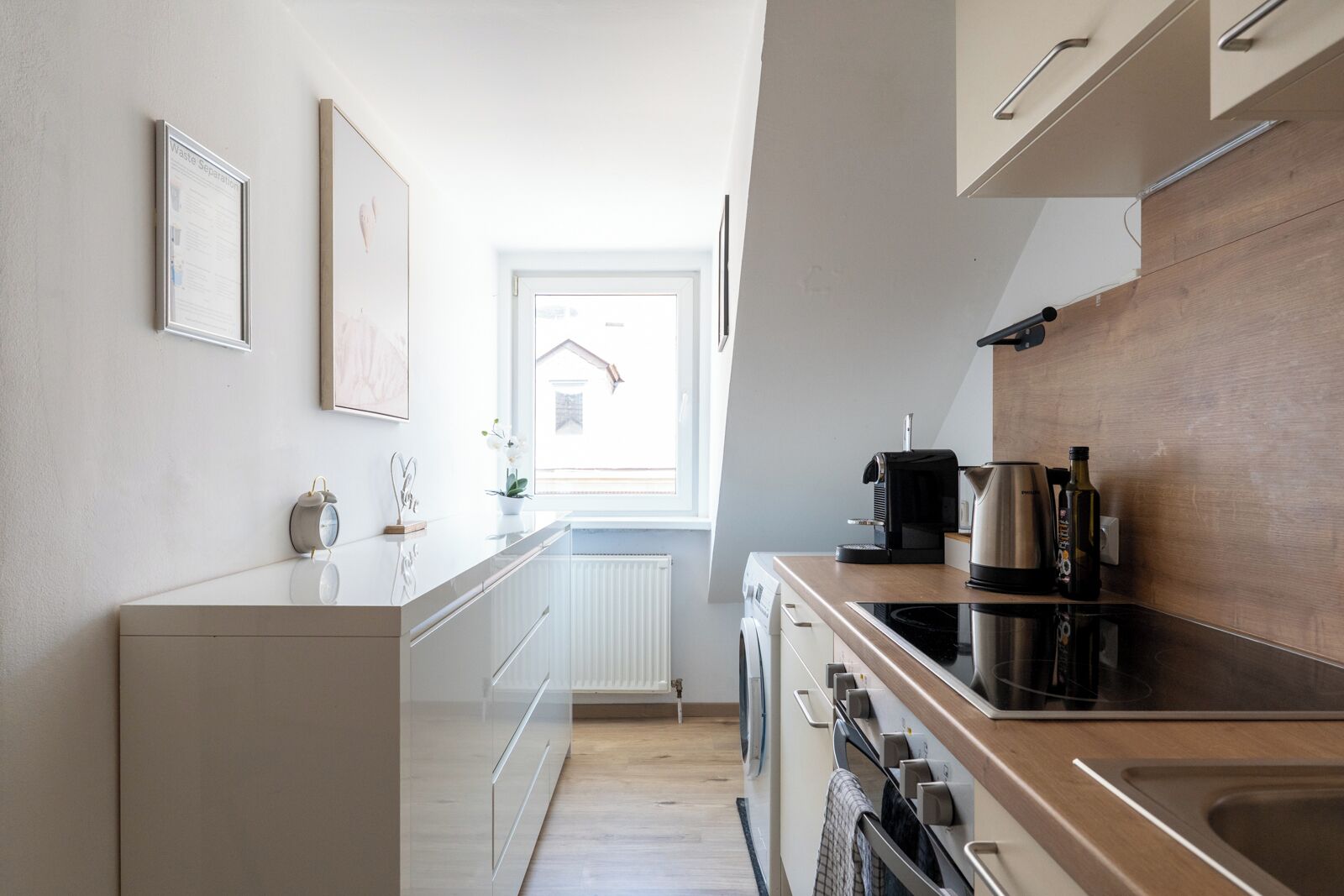 Una cocina moderna con horno integrado, cafetera y hervidor sobre la encimera.