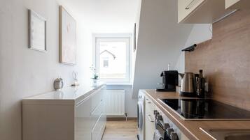 Una cocina moderna con horno integrado, cafetera y hervidor sobre la encimera.
