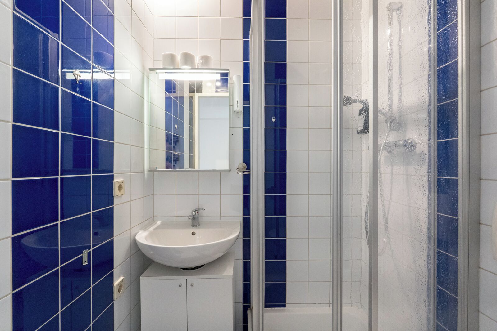 A bathroom with a white sink, a mirror, and a glass-enclosed shower.