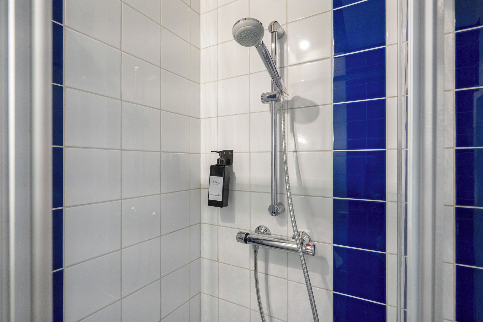 Ducha con cabezal de ducha de mano, grifo empotrado, dispensador de jabón y panel de control.