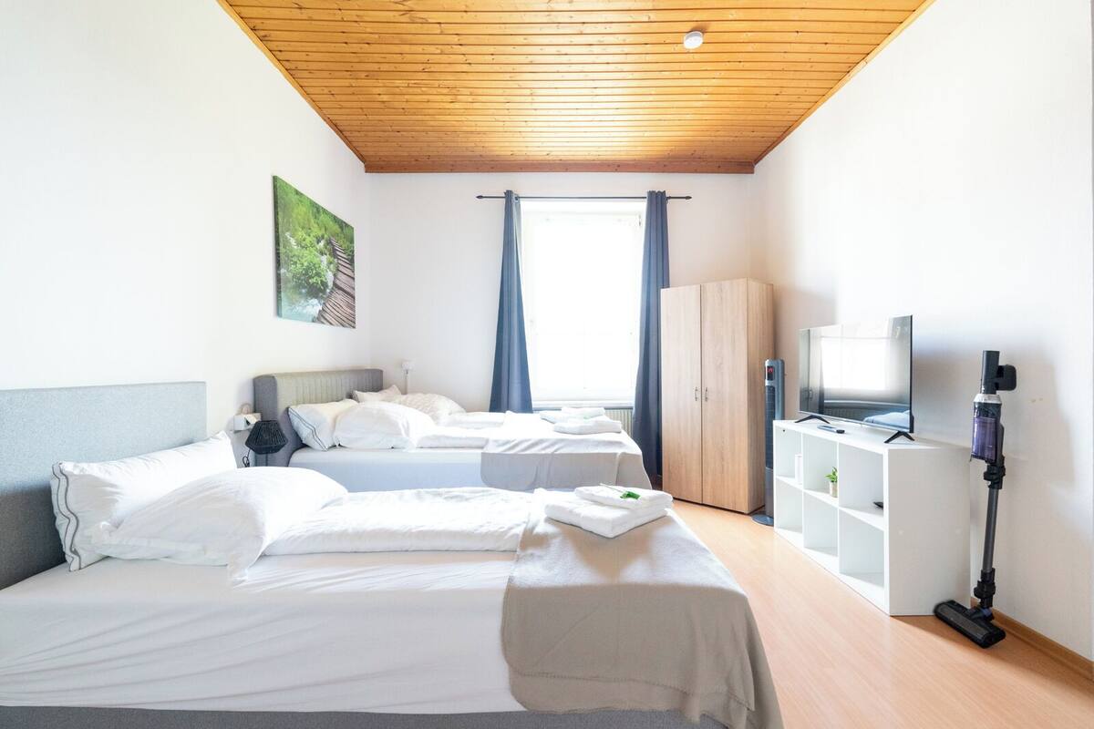 A hotel room with two beds, a TV, a cabinet, and a ceiling fan.
